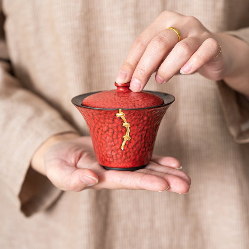 Person holding red kintsugi-style ceramic cup