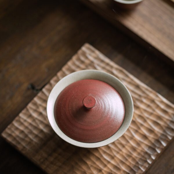 Clay teapot lid on textured wooden tray.