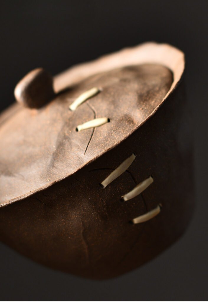 Brown clay pot with decorative stitching details.