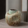 Antique textured ceramic vase on wooden surface.