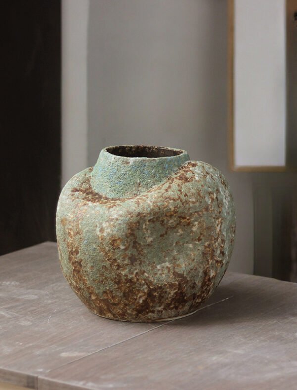 Antique textured ceramic vase on wooden surface.