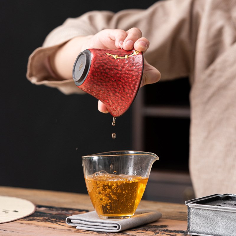 Pouring tea from red cup into glass