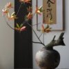 Japanese ikebana floral arrangement in rustic vase.