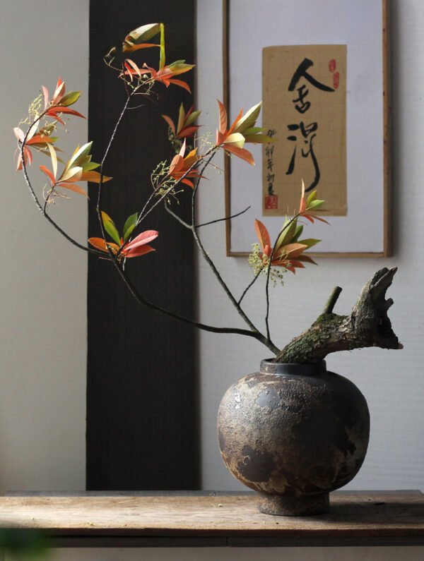 Japanese ikebana floral arrangement in rustic vase.