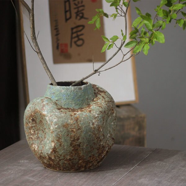 Rustic vase with branches on wooden table.