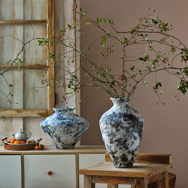 Artistic vases with branches on rustic furniture.