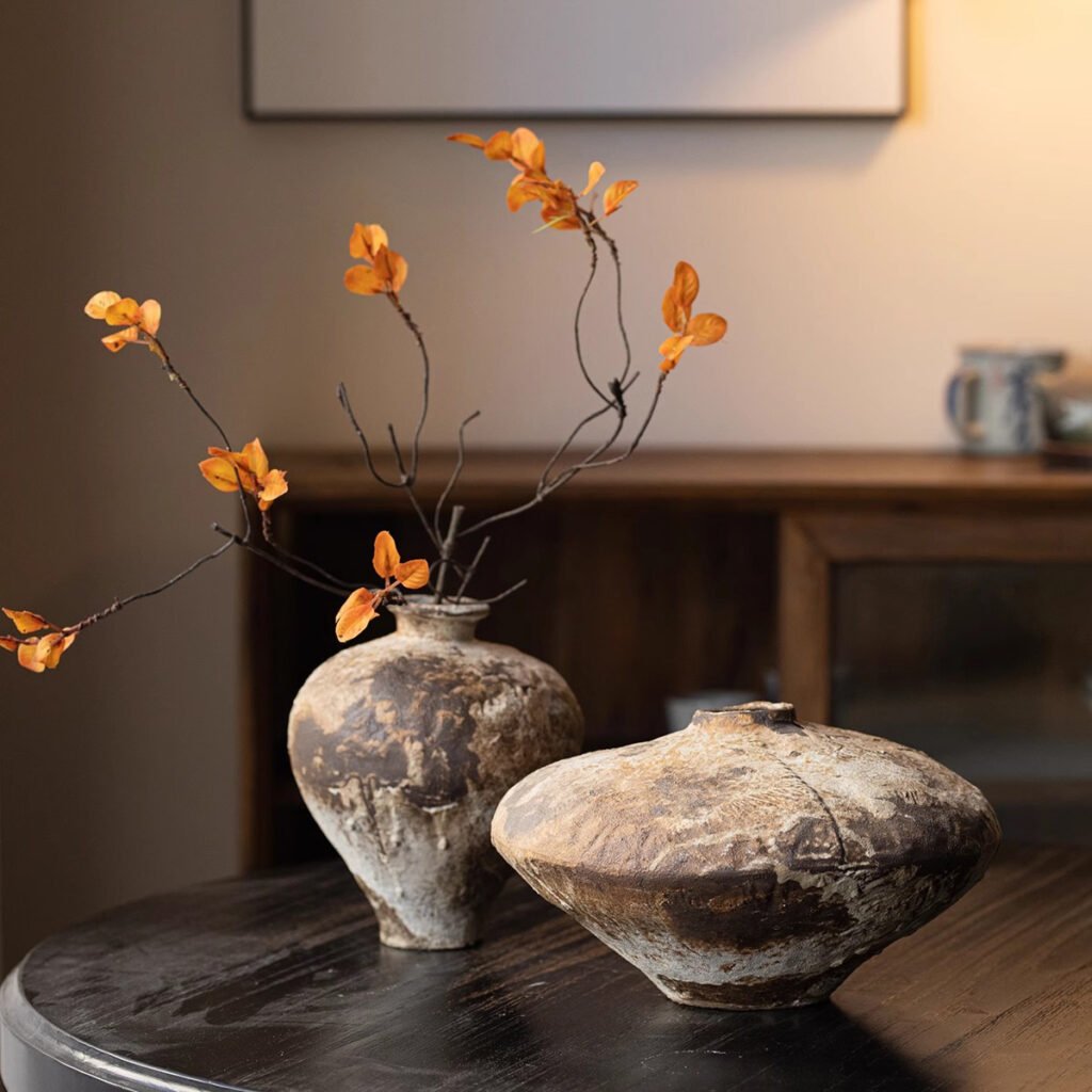Rustic vases with orange leaves on table.
