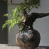 Rustic vase with branches and leaves on table.