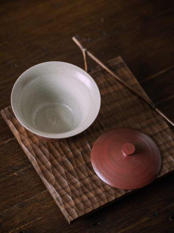 Ceramic teacup with lid on wooden tray
