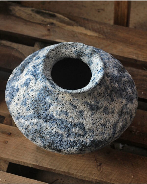 Blue speckled ceramic vase on wooden surface.
