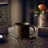 Rustic mug with coffee beans on wooden table