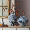 Blue vases with branches and orange fruits.