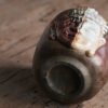 Ceramic cup with half Buddha face on table.
