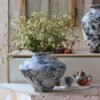 Stone vase with wildflowers on wooden table.