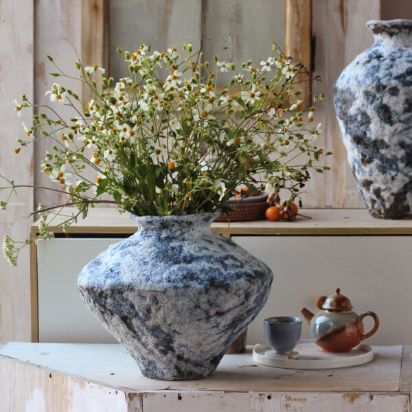 Stone vase with wildflowers on wooden table.