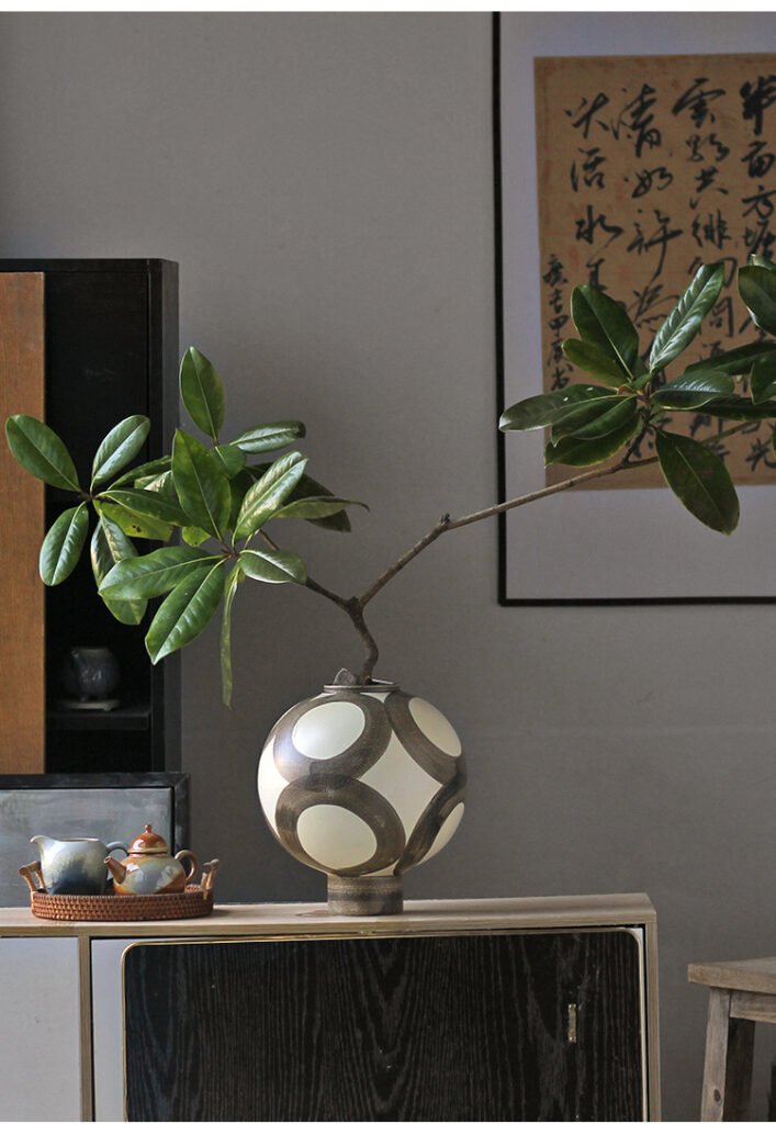 Artistic vase with plant on cabinet
