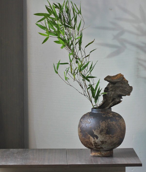 Rustic vase with bamboo and driftwood decoration.