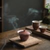 Ceramic teaware on wooden table with steam.