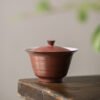 Red ceramic teacup with lid on table