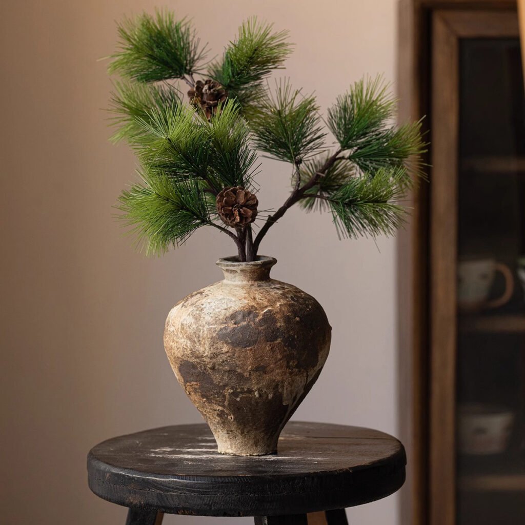 Rustic vase with pine branches on stool