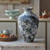 Textured ceramic vase on rustic table with teapot.